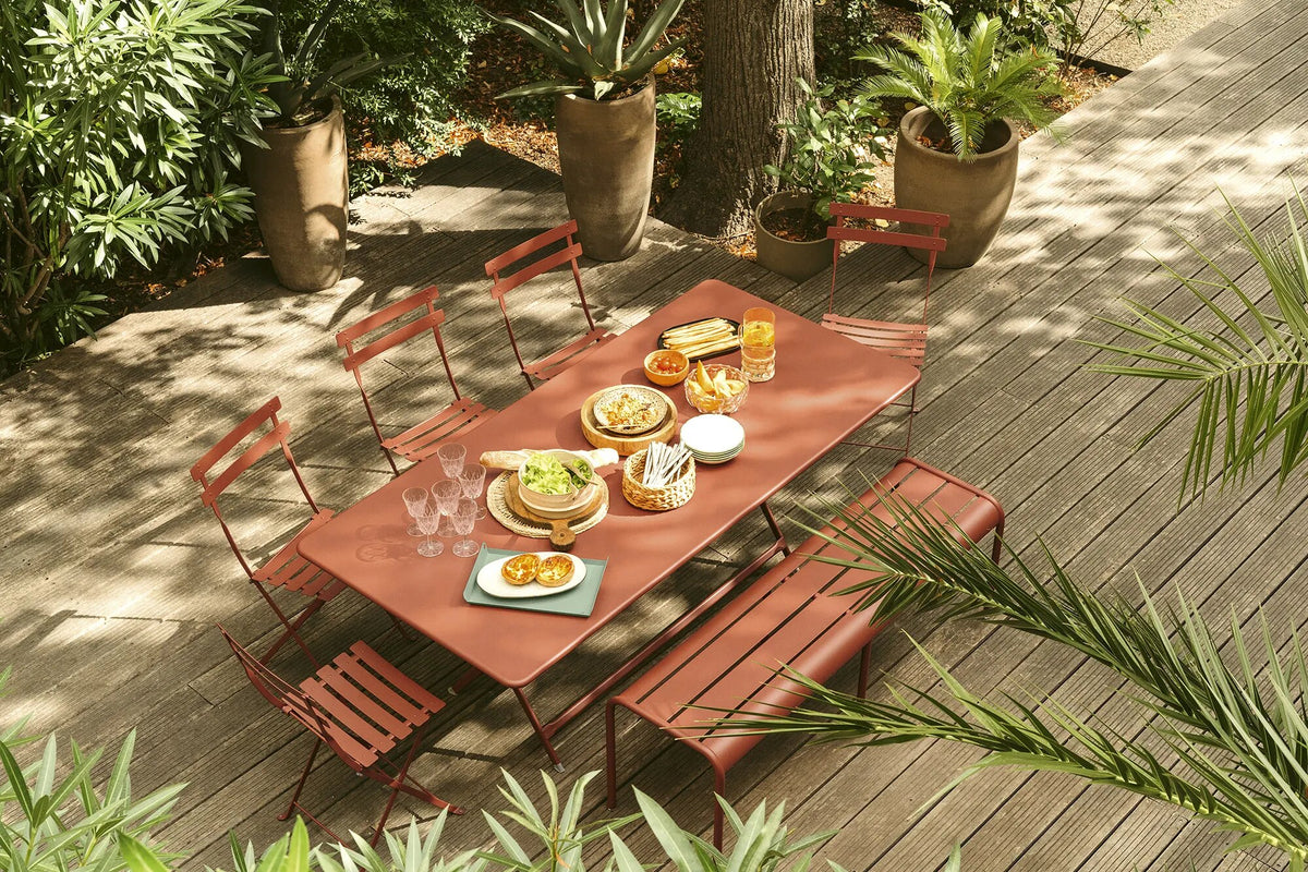 Fermob Bistro folding chairs and rectangular table in red ochre on a shaded deck with terracotta pots