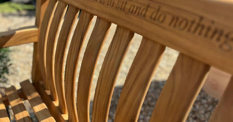 Inscribed teak garden bench on a lawn, personalised with an engraved dedication, at Cedar Nursery Cobham Surrey